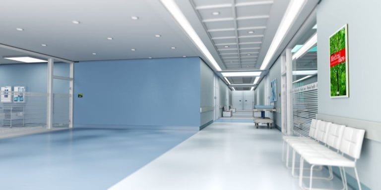 Rendered medical clinic corridor with blue-grey flooring, glazed rooms and a waiting bench
