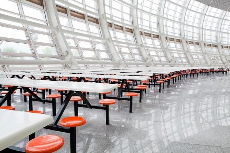 Shared food-court seating with orange stools, tables and a wide circulation aisle