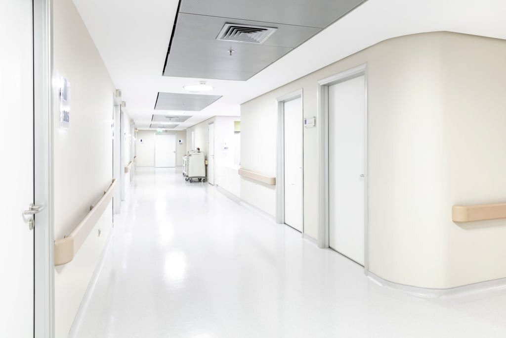 Empty healthcare corridor with a smooth grey floor and bright walls
