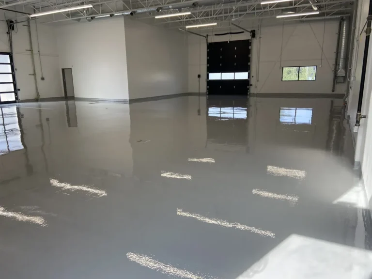 Reflective solid-grey resin floor in a commercial shop with overhead lighting and overhead doors