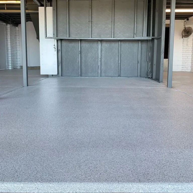 Grey flake floor at the entrance to a large interior with a metal-framed wall.