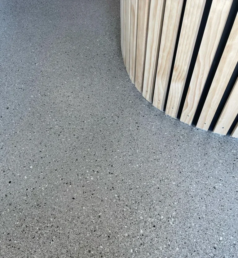 Grey decorative flake floor meeting a curved vertical timber feature.