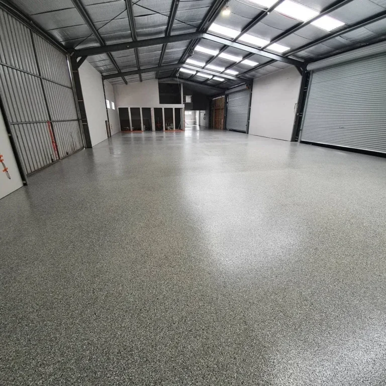Grey flake flooring inside a metal-framed workshop with roller doors.