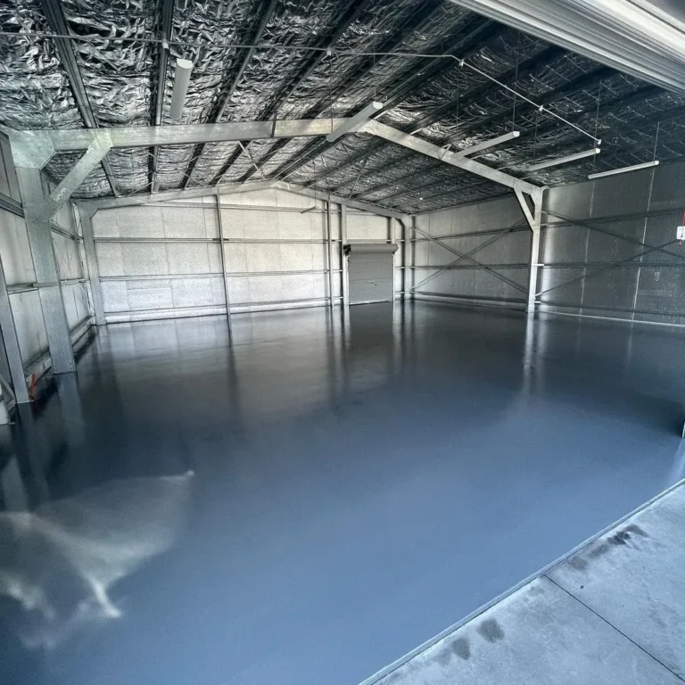 Grey industrial coating across a workshop floor beneath an exposed roof.