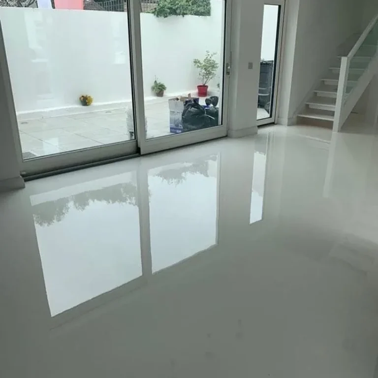 White reflective floor beside a staircase and full-height glazed doors.