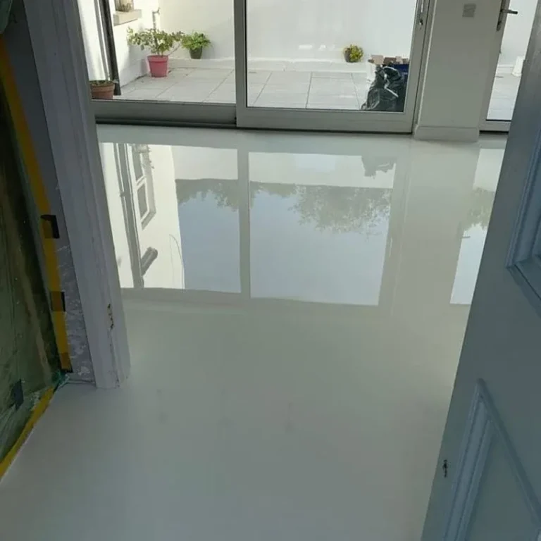 High-gloss white residential floor reflecting large glazed doors.