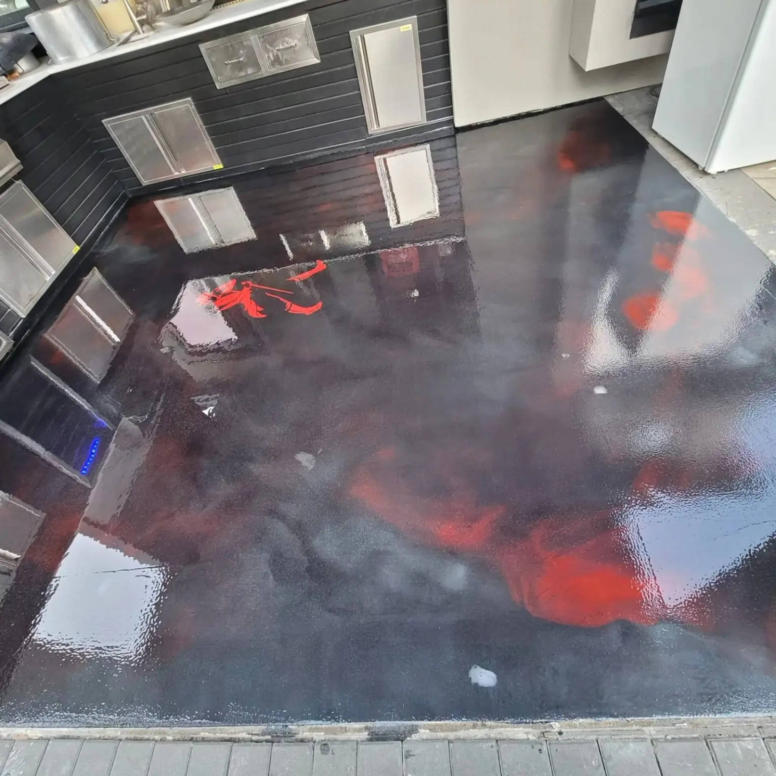Black and red metallic epoxy floor with a custom red graphic