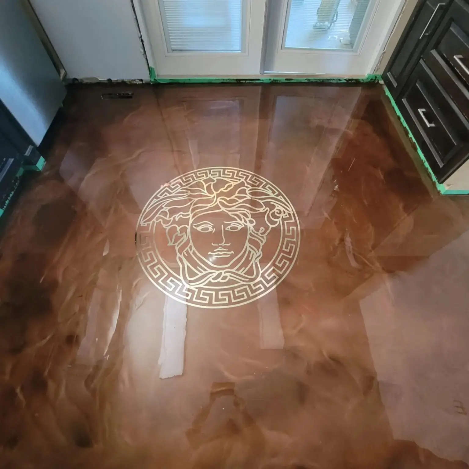 Bronze metallic epoxy floor with a custom Medusa-style centre graphic