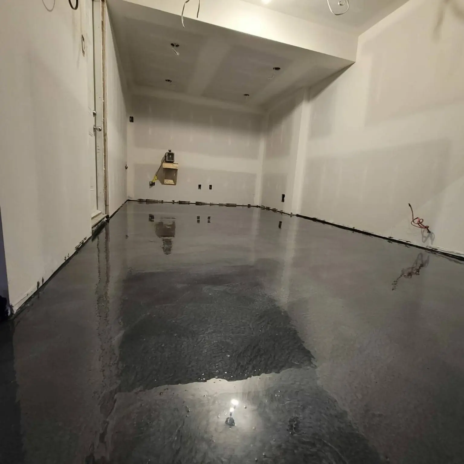 Dark grey metallic epoxy floor in an unfinished interior