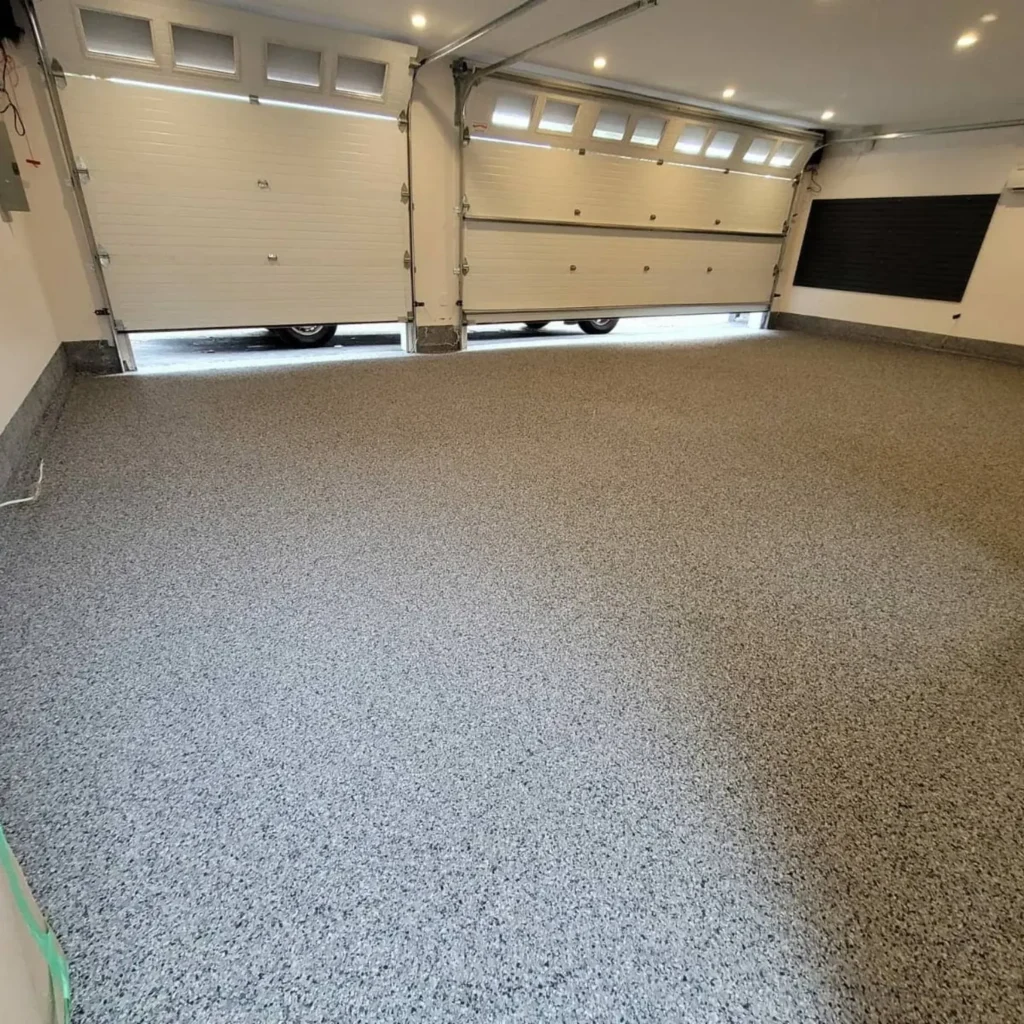 Grey decorative flake floor across a garage with two overhead doors