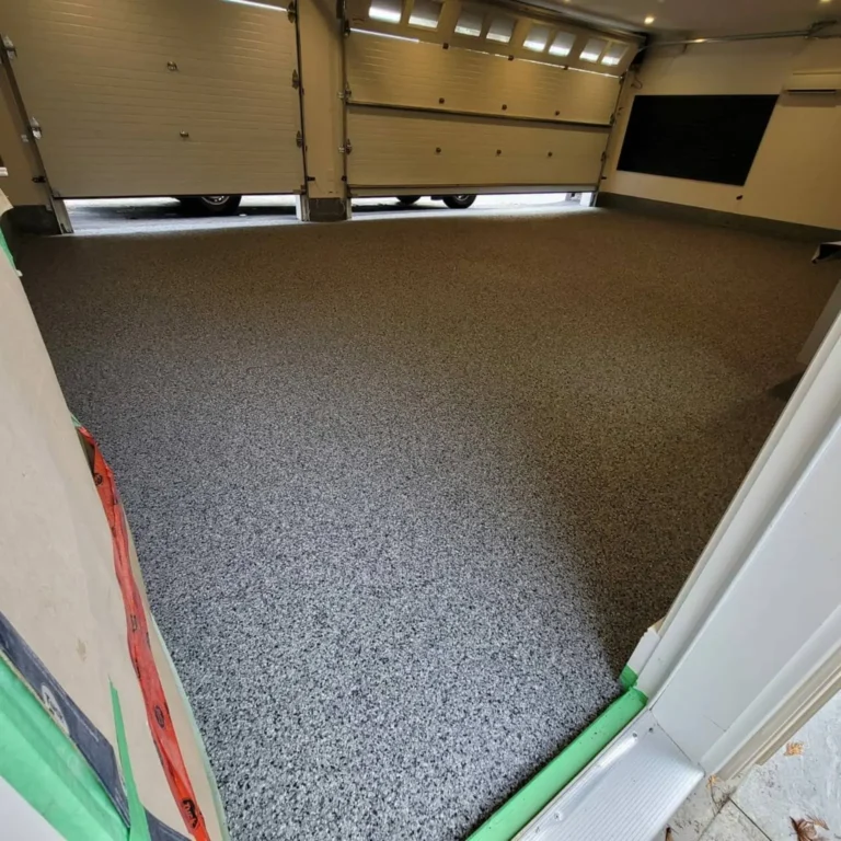 Grey full-flake garage flooring viewed from the entrance toward two overhead doors