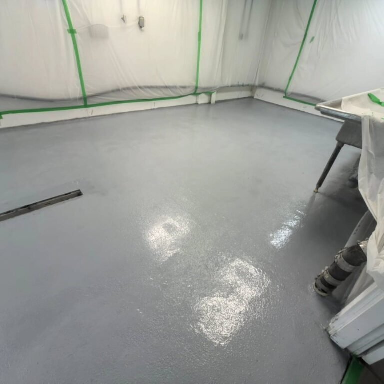 Grey resin-coated floor with a drain and protected surrounding equipment