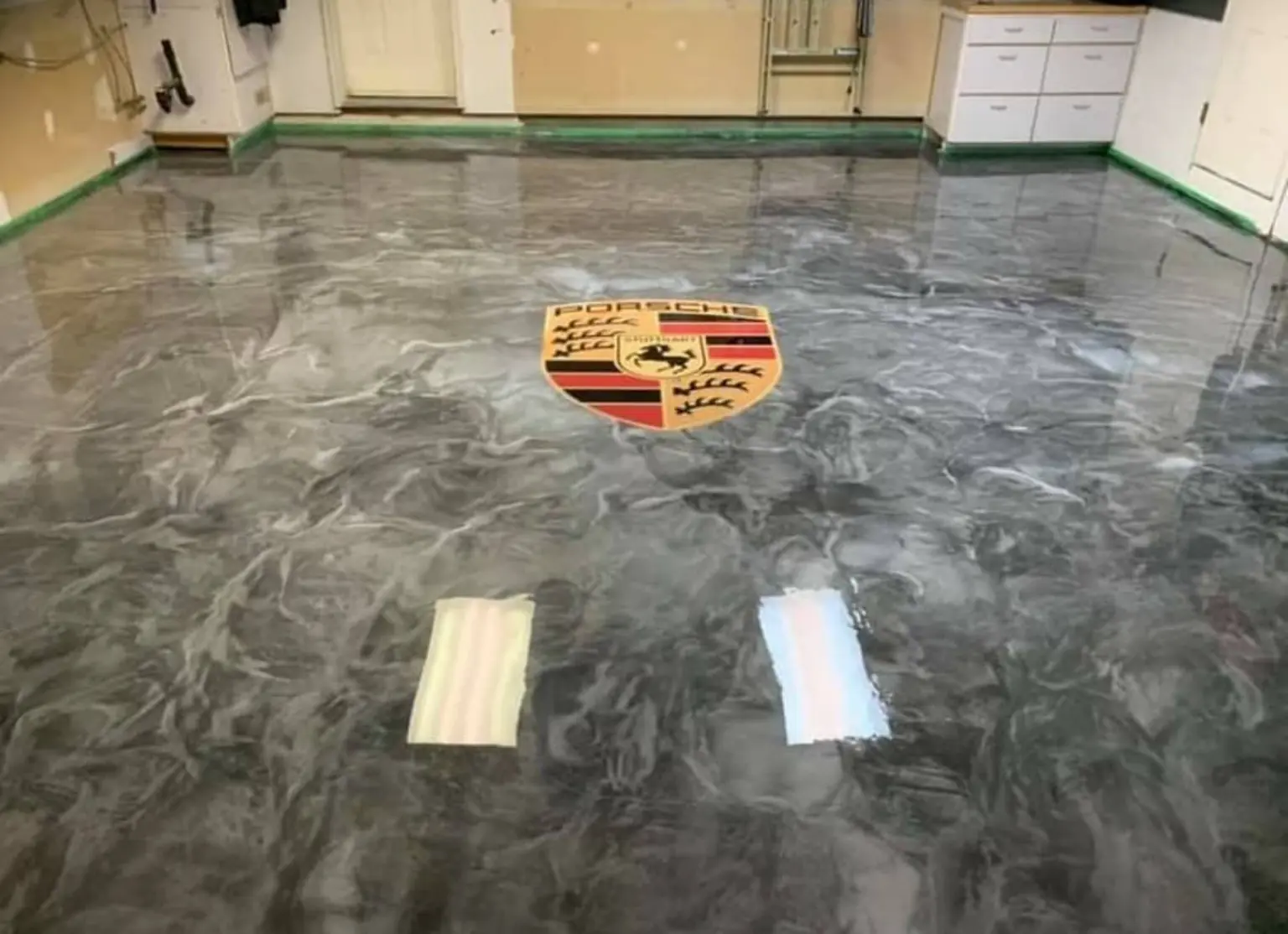 Grey and black metallic epoxy garage floor with a custom Porsche crest