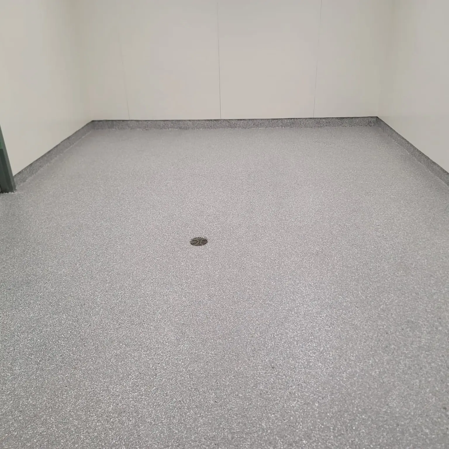 Close view of a textured urethane cement floor with integral cove and drain installed in Yaletown Vancouver