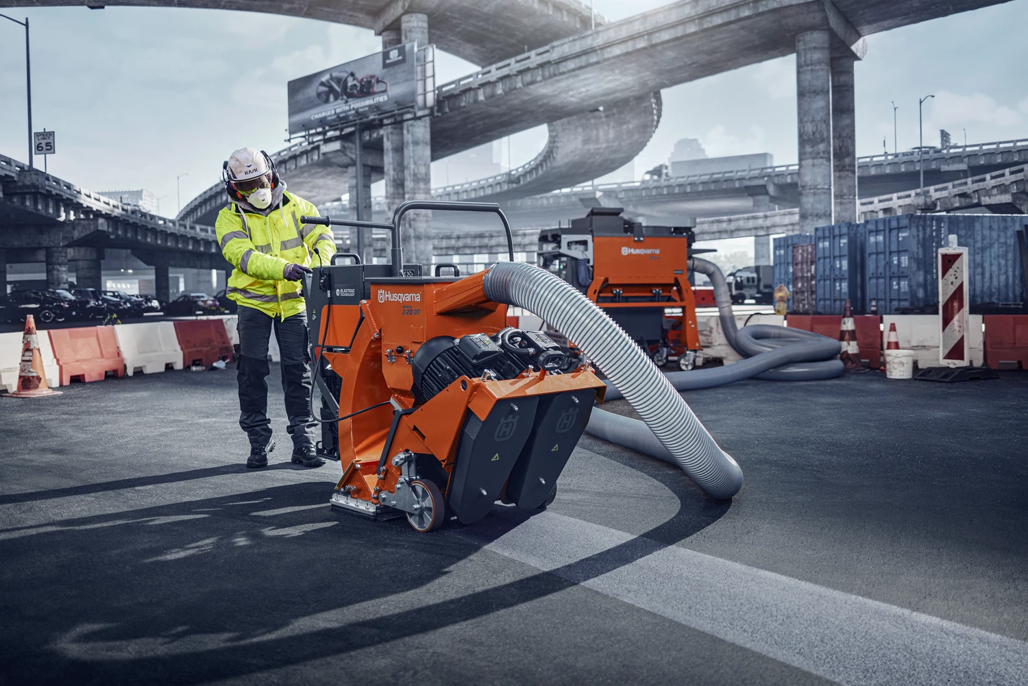Operator using industrial surface preparation equipment with connected dust extraction outdoors
